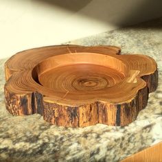 a wooden bowl sitting on top of a counter next to a marble countertop with wood slices in it