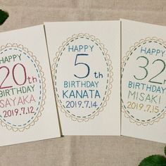 three birthday cards with the number twenty five and two different designs on them, sitting next to some green leaves