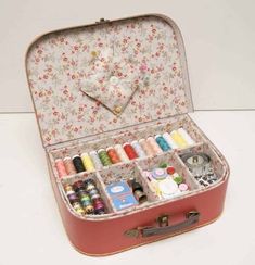 an open suitcase filled with lots of crafting supplies on top of a white table