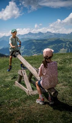 two children playing on a wooden structure in the mountains