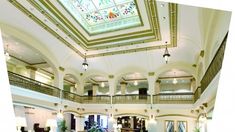 a large lobby with high ceilings and stained glass windows on the second floor is shown