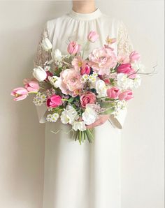 a woman holding a bouquet of pink and white flowers