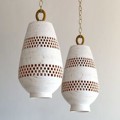 two white vases hanging from chains on a wall