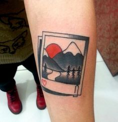 a small tattoo on the arm of a person with mountains and trees in it,