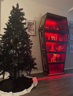 a small christmas tree is lit up with red lights in front of a bookshelf