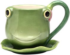 a green frog mug sitting on top of a saucer with its eyes wide open