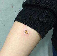 a person with a small tattoo on their arm that has a yellow cat on it