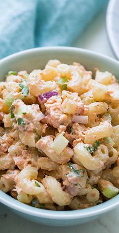 a bowl filled with macaroni salad on top of a white countertop next to a blue towel