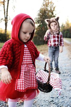 two young children dressed up in costumes walking down a gravel road with an empty basket