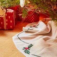 a christmas tree with presents under it on the floor next to a white towel and red box