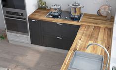 a kitchen with wooden counter tops and stainless steel appliances on the wall, along with an oven