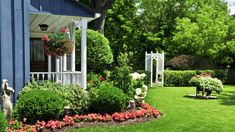 a blue house with flowers and statues in the front yard