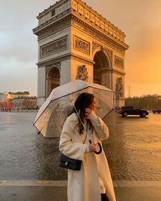 a woman is standing in front of the arc de trio triumph with her umbrella up