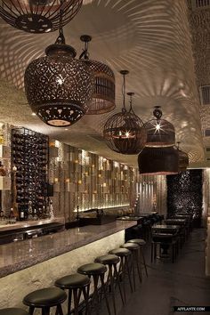 a bar with lots of stools and lights hanging from the ceiling