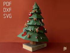 a green christmas tree on top of a stack of books with the words dxf svg below it