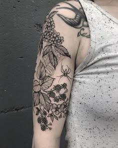 a woman's arm with black and white tattoos on her left arm, which is covered in flowers