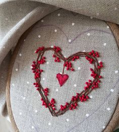 a close up of a heart on a piece of cloth with red beads and thread