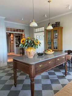 a kitchen with a checkered floor and two vases filled with flowers on the island