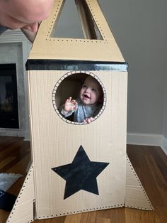 a man looking at a cardboard box with a baby in it's mouth and a black star on the side