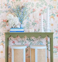 a table with flowers and vases on top of it next to a wall paper