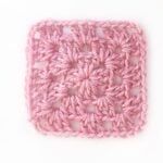 a pink crocheted square on a white background