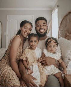 a man, woman and child are sitting on a bed with their arms around each other