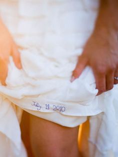 a person in a white dress holding something with the words fabulous ideal something blue - wedding date stitched into the wedding gown