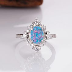 When it comes to the most stunning jewelry designs, we absolutely adore our gorgeous Mei white fire opal ring design. We've made each ring with love by hand  using our premium sterling silver.  Finished with beautiful natural crystals, it's a design we know you will adore. ✦ DETAILS ✦ ✧ Blue fire opal and natural crystals  ✧ Sizes 3.75-4.25 ✧ This ring  will arrive ready to gift in a Kherish Jewelry Pouch. ✧ Due to the nature of the handmade process, each piece may slightly vary in color, size, Opal Jewelry With Halo Setting For Gift, Opal Ring With Halo Design As A Gift, Gift Opal Ring With Halo Design, Opal Jewelry With Accent Stones As A Gift, Blue Opal Jewelry For Wedding, Opal Jewelry With Accent Stones For Gift, Pink Opal Jewelry For Anniversary, Round Pink Opal Jewelry For Anniversary, Opal Ring With Cubic Zirconia Accent Stones For Gift