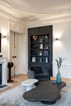 a living room filled with furniture and a fire place next to a book shelf on top of a hard wood floor