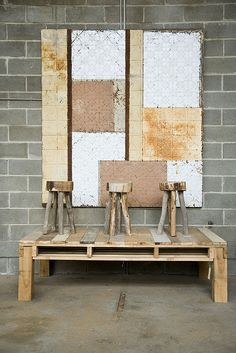 three pieces of wood sitting on top of a wooden bench in front of a brick wall