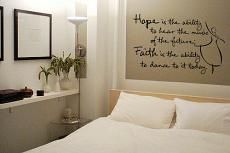 a bed with white sheets and pillows in a bedroom next to a wall mounted poster