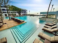 an outdoor swimming pool with lounge chairs and palm trees