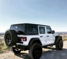 a white jeep parked on top of a dirt road