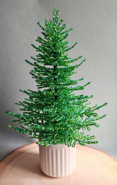 a small green christmas tree sitting on top of a wooden table