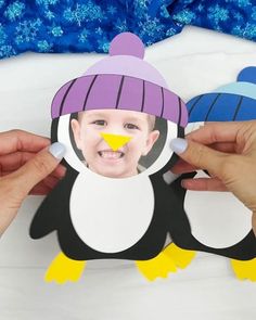 someone holding up a cutout of a penguin with a hat on it's head