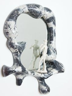 a mirror that has a statue in front of it