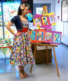 a woman standing in front of a sign that says art show on the easel