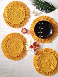 three yellow plates sitting on top of a table next to a candle and some flowers