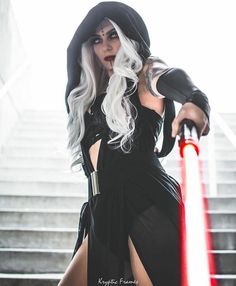 a woman dressed as darth vader holding a light saber