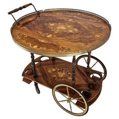 an antique wooden serving cart with wheels and floral designs on the top, from the early 20th century