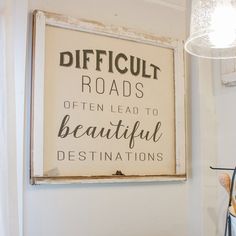 a sign that reads difficult roads often lead to beautiful destinations hanging on the wall next to a lamp