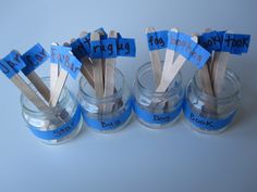 four glass jars with toothpicks in them on a blue tablecloth covered surface