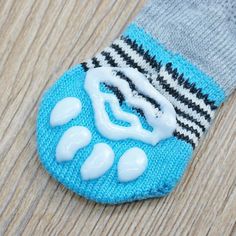 a close up of a knitted animal's paw on a wooden floor with a sock