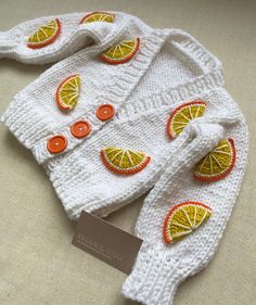 a knitted sweater with oranges and buttons on it