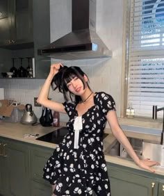 a woman standing in a kitchen next to a stove top oven with her hands on her head