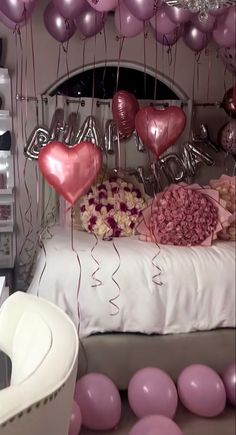 a bed with pink and purple balloons hanging from the ceiling