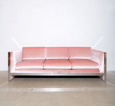 a pink couch sitting on top of a hard wood floor next to a white wall