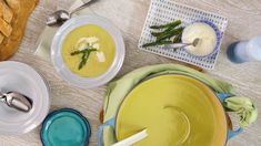 there are bowls and plates on the table with food in them, along with bread