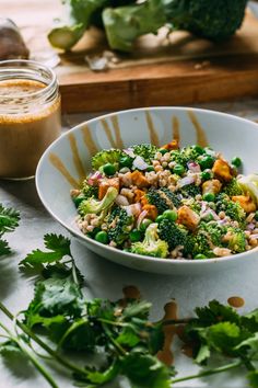 a white bowl filled with broccoli, beans and other vegetables on top of a table