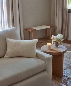 a living room with two white couches and a coffee table in front of the window